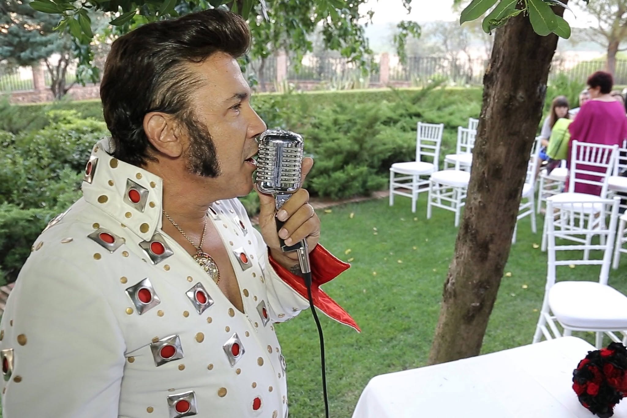 Marcos Elvis cantando con micrófono clásico durante una ceremonia