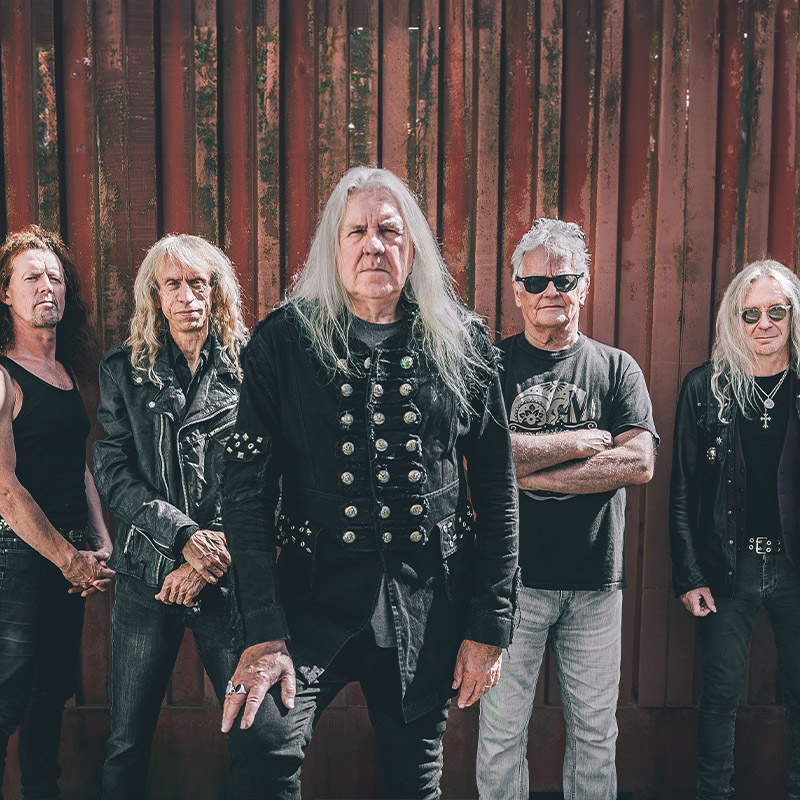 Cartel oficial de Saxon en el Stone & Music Festival 2027 sobre una estatua alada y el Teatro Romano de Mérida