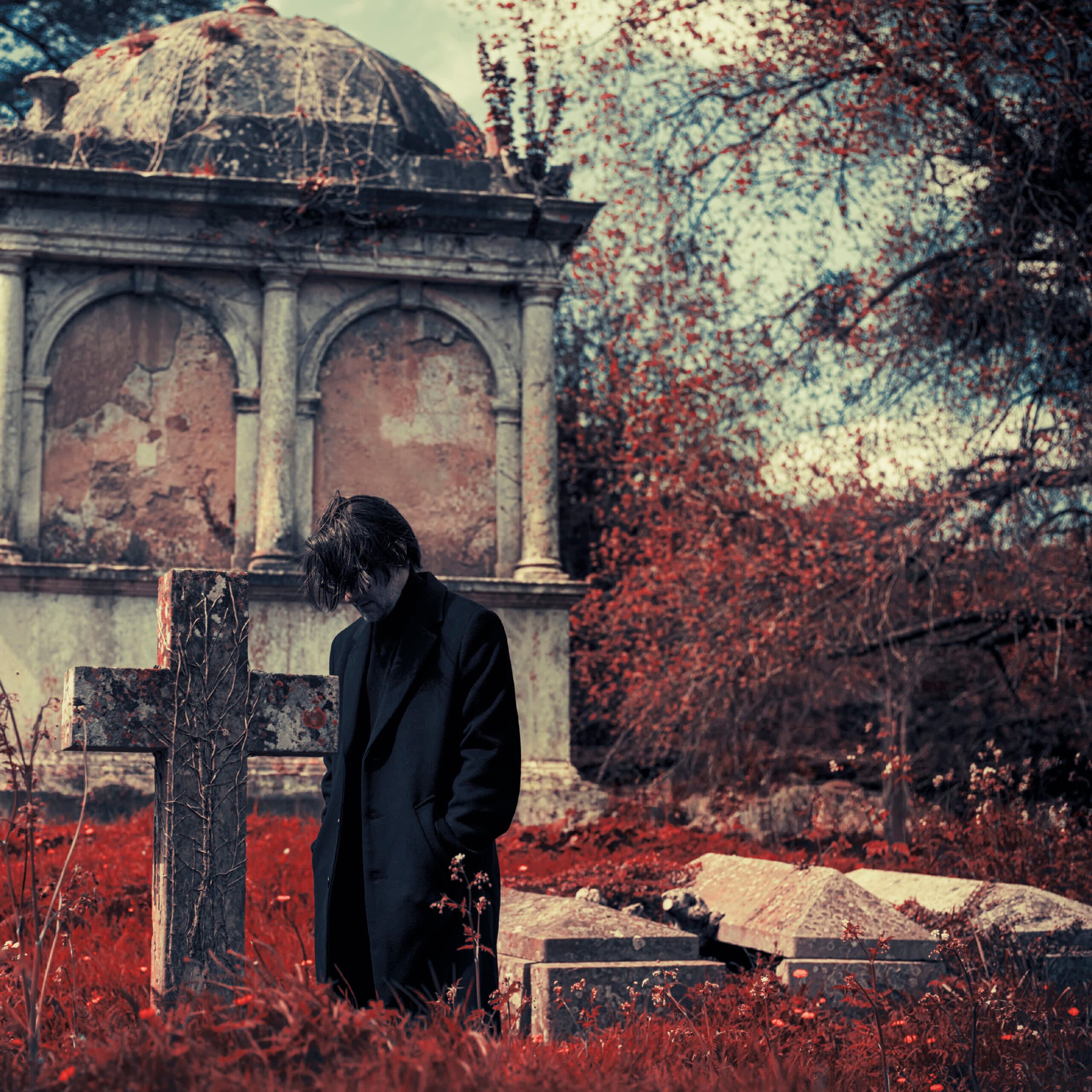 Steven Wilson junto a una cruz de piedra en la imagen oficial de Requiem For A Village